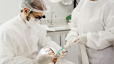 A man and woman in white coats attend to a patient in a medical setting, focused on providing care.