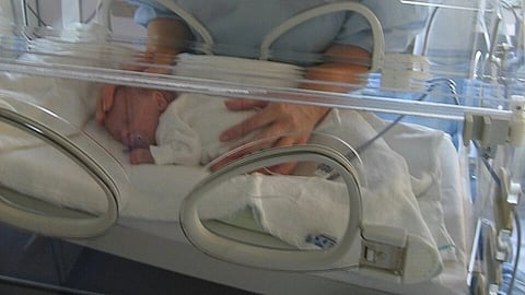 A newborn baby in an incubator.