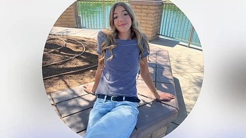 Sabrina Burlando sitting outdoors wearing a grey top and light blue jeans.