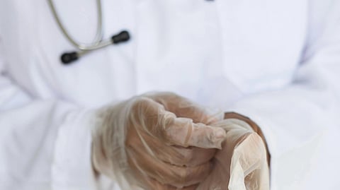 Doctor carefully removing surgical gloves after a medical procedure.