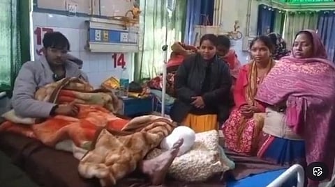 Suraj on hospital bed and surrounded with family.