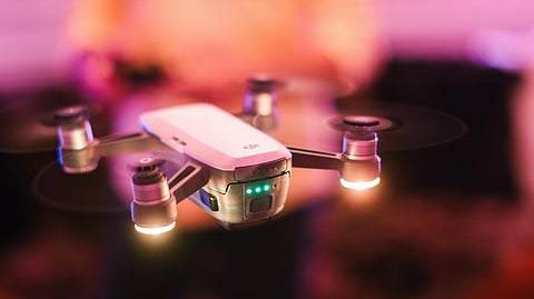 3D illustration of a drone hovering in front of a blurred background, with its lights illuminated.