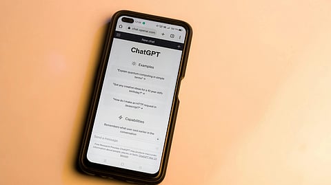 A smartphone displaying ChatGPT’s main interface against a solid pink background.