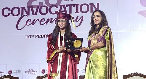 Actress Sreeleela in red robe receiving her degree on a stage from another lady in saree.