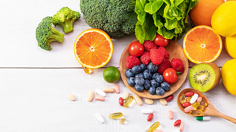 Colorful fruits and vegetables with supplements displayed on a white background.