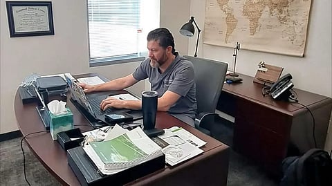 An Image of Dr. Douglas Hansen in his office in grey scrubs.