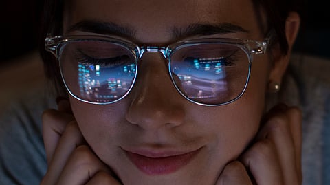 A woman with glasses, looking thoughtfully to the side, showcasing her stylish eyewear and confident expression.