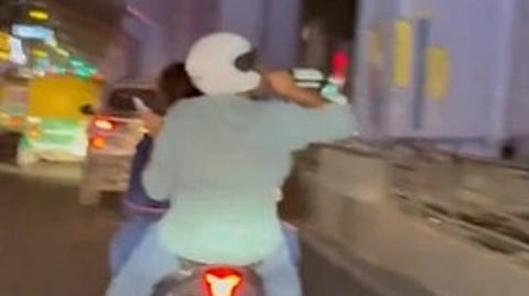 A person in mint green shirt, wearing a white helmet and drinking from a green bottle on a bike.