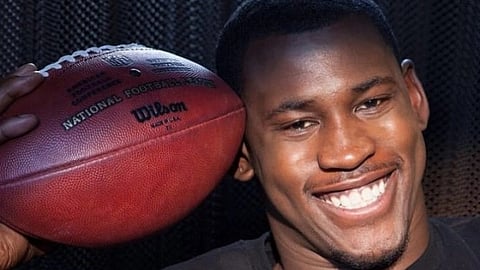Aldon holding a football near his face.