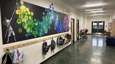 A wide shot of a brightly lit school hallway with polished green floors.