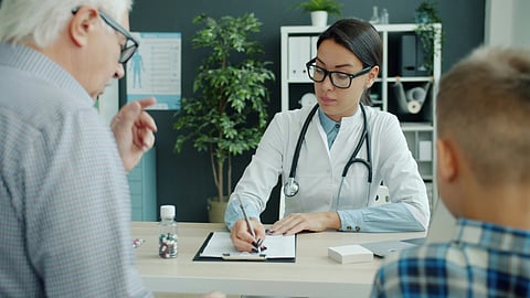 A female doctor interviewing a elderly male patient and filling out a form