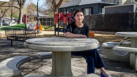 A woman sits at a picnic table in a park.