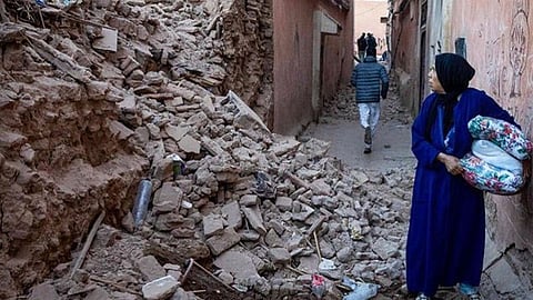 മൊറോക്കോയിൽ ഭൂചലനത്തിൽ തകർന്നു വീണ കെട്ടിടത്തിന്റെ അവശിഷ്ടങ്ങൾക്കിടയിലൂടെ രക്ഷപ്പെടുന്ന സ്ത്രീ.