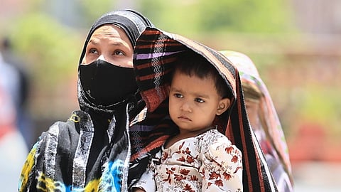 A woman covers her child in protection from the scorching sun on a hot summer day, in Jaipur, Saturday, May 25, 2024.