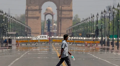 A pedestrian carries a water bottle on a hot summer day, at the Kartavya Path in New Delhi, Monday, April 7, 2025.