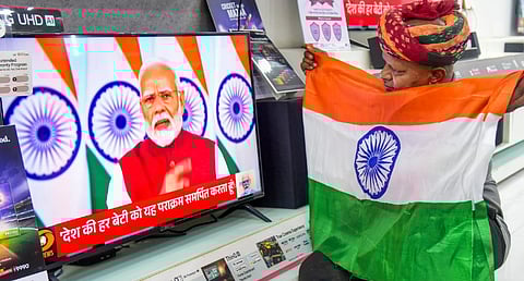 A man holds the national flag as he watches the live telecast of Prime Minister Narendra Modi's address to the Nation, in Bikaner, Monday, May 12, 2025.