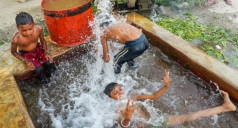 Children cool off in a tubewell on a hot summer day, in New Delhi, Monday, June 9, 2025.