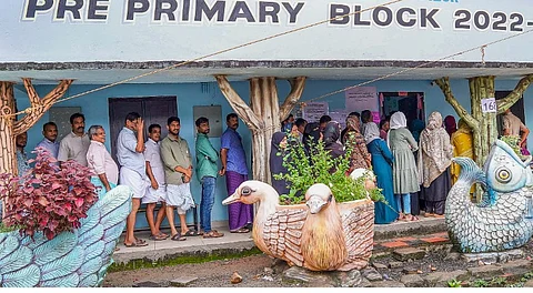 People wait in a queue to cast their votes during the Nilambur Assembly by-election, at GMLP School, in Malappuram district, Kerala, Thursday, June 19, 2025.
