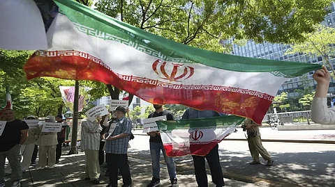 People hold the Iranian flags and signs during a rally demanding to stop the war between Israel and Iran, in Seoul, South Korea, Sunday, June 22, 2025.
