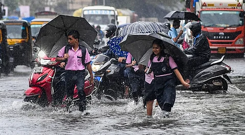 Commuters make their way through a waterlogged road amid rainfall, in Mumbai, Monday, Aug. 18, 2025.