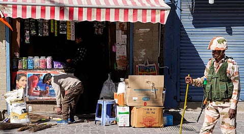 A security officer stands guard outside a shop at a market during a four-hour relaxation in the curfew, in Leh, Tuesday, Sept. 30, 2025.