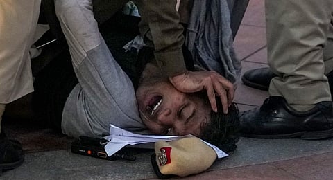 Police personnel try to control a violent person during a protest against worsening air quality in the national capital, at the India Gate, in New Delhi, Sunday, Nov. 23, 2025.