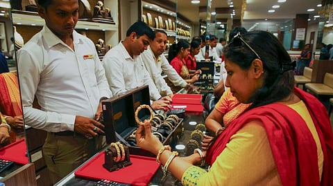 A woman checks a gold ornament at a jewellery showroom ahead of 'Dhanteras' festival, in Agartala, Thursday, Oct. 9, 2025.