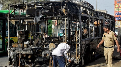 A policeman inspects a burnt DTC bus after it hit multiple vehicles in Outer Delhi's Nangloi area, in New Delhi, Monday, March 9, 2026.