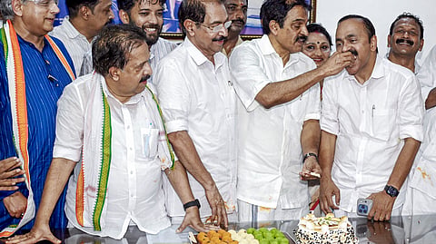 Leader of the Opposition VD Satheesan accepts sweets from KC Venugopal following the Kerala Assembly election results, while senior leaders including Shashi Tharoor, Ramesh Chennithala and Sunny Joseph look on.