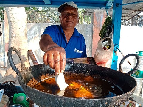 A man fries samosas in a large pan of oil in India. Palm oil is relatively inexpensive but its health benefits are contested. (Image: Alamy)