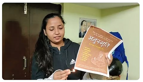 “द मूकनायक” की फाउंडर मीना कोटवाल मनुस्मृति को जलाते हुए/ फोटो साभार: @KotwalMeena