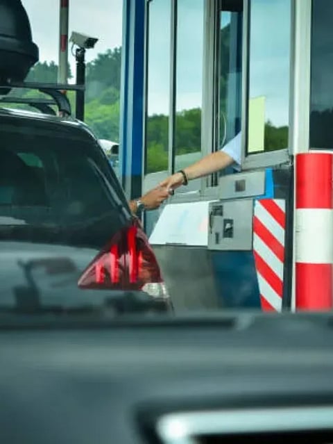 A man pays money to a cashier for a toll road Toll gate motorway entrance