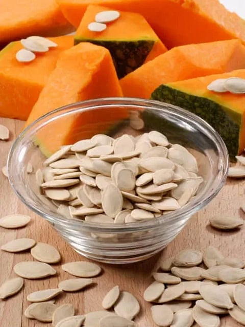 Toasted dry pumpkin seed on pumpkin vegetable background.