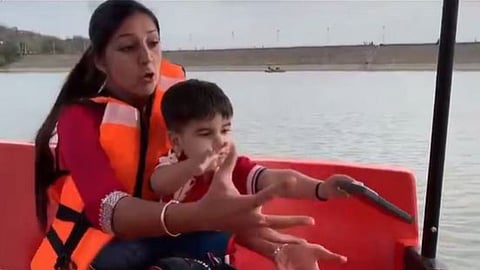 A child threw his mother's iPhone into a lake during a boating trip, and her shocked reaction has gone viral on social media.