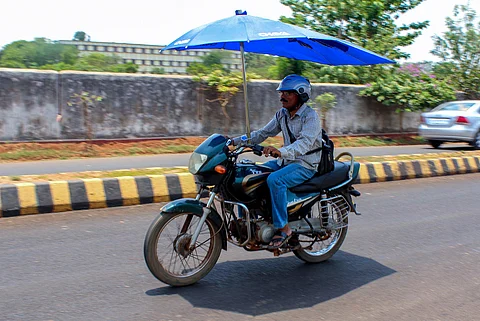 A man riding a motorcycle with a bike umbrella fitted on it in Bhubanewswar