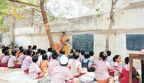 A teacher conducts classes for students at the Government Primary School, Bottuguda, in Nalgonda under the shade of trees on Tuesday.