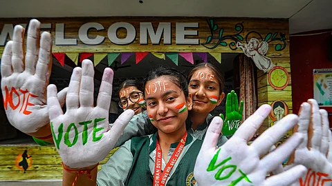 School students with their faces and hands painted as part of voter awareness campaign pose for photos, ahead of Lok Sabha polls, in Jammu.