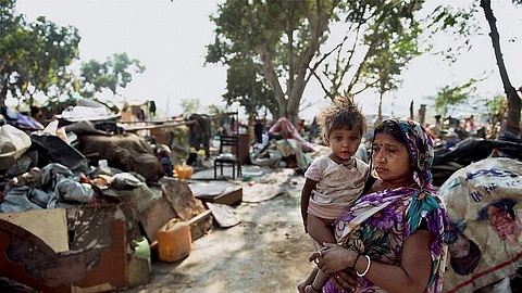 A woman holding her kid stands amid household items at Shakur Basti, where a demolition drive was carried out in a slum, in New Delhi.