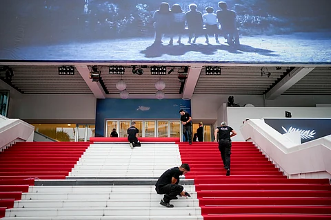 Festival workers lay the red carpet at the Palais des Festivals on opening day of the 77th international film festival, Cannes, southern France, Tuesday, May 14, 2024.