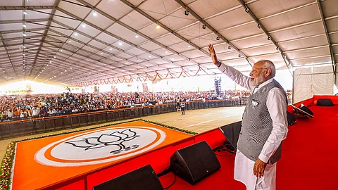 Prime Minister Narendra Modi waves to supporters during a public meeting for Lok Sabha elections, in Anand.