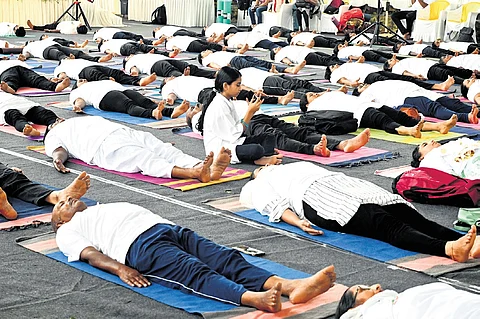A girl clicking a photograph on her mobile phone amid a yoga session organised by the National Ayush Mission-Kerala at Central Stadium in Thiruvananthapuram as part of the International Yoga Day observance on Friday