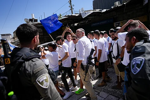 Israeli border police officers look at armed Israeli civilians during a march marking Jerusalem Day, in Jerusalem's Old City, Wednesday, June 5, 2024.