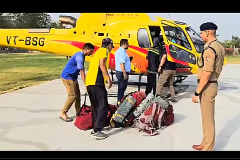 Rescue officials are seen boarding a helicopter as they search for a trekking group that became lost due to severe weather conditions in Uttarkashi, Uttarakhand.
