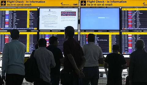Passengers look at screens, one of them showing Blue Screen error, at T3 Terminal of the Indira Gandhi International Airport