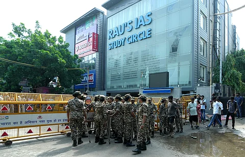 Security personnel stand guard near a UPSC exam coaching centre after three civil services aspirants died in the basement flooding,