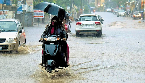 Commuters cross a waterlogged road in Karimnagar on Sunday
