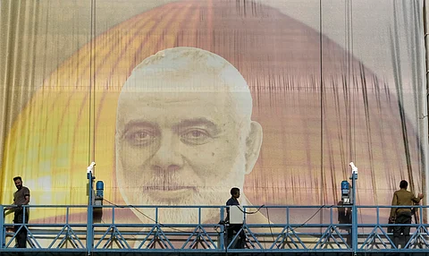 Iranian workers install a huge banner on a wall showing a portrait of Hamas leader Ismail Haniyeh and the Dome of Rock Mosque at the Al-Aqsa Mosque compound of Jerusalem at Palestine.