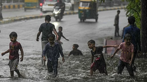 Children play on a waterlogged road in New Delhi.
