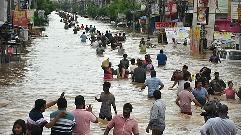 Residents of Singh Nagar wade through the flood after the Budameru canal breach in Vijayawada on Sunday.