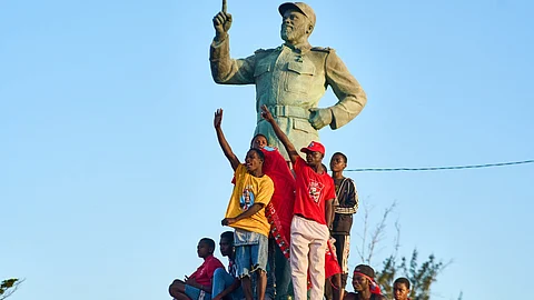 Supporters of Mozambique Liberation Front (FRELIMO) party climb on a statue of former President of Mozambique Samora Machel attend a rally on in Beira on October 6, 2024.